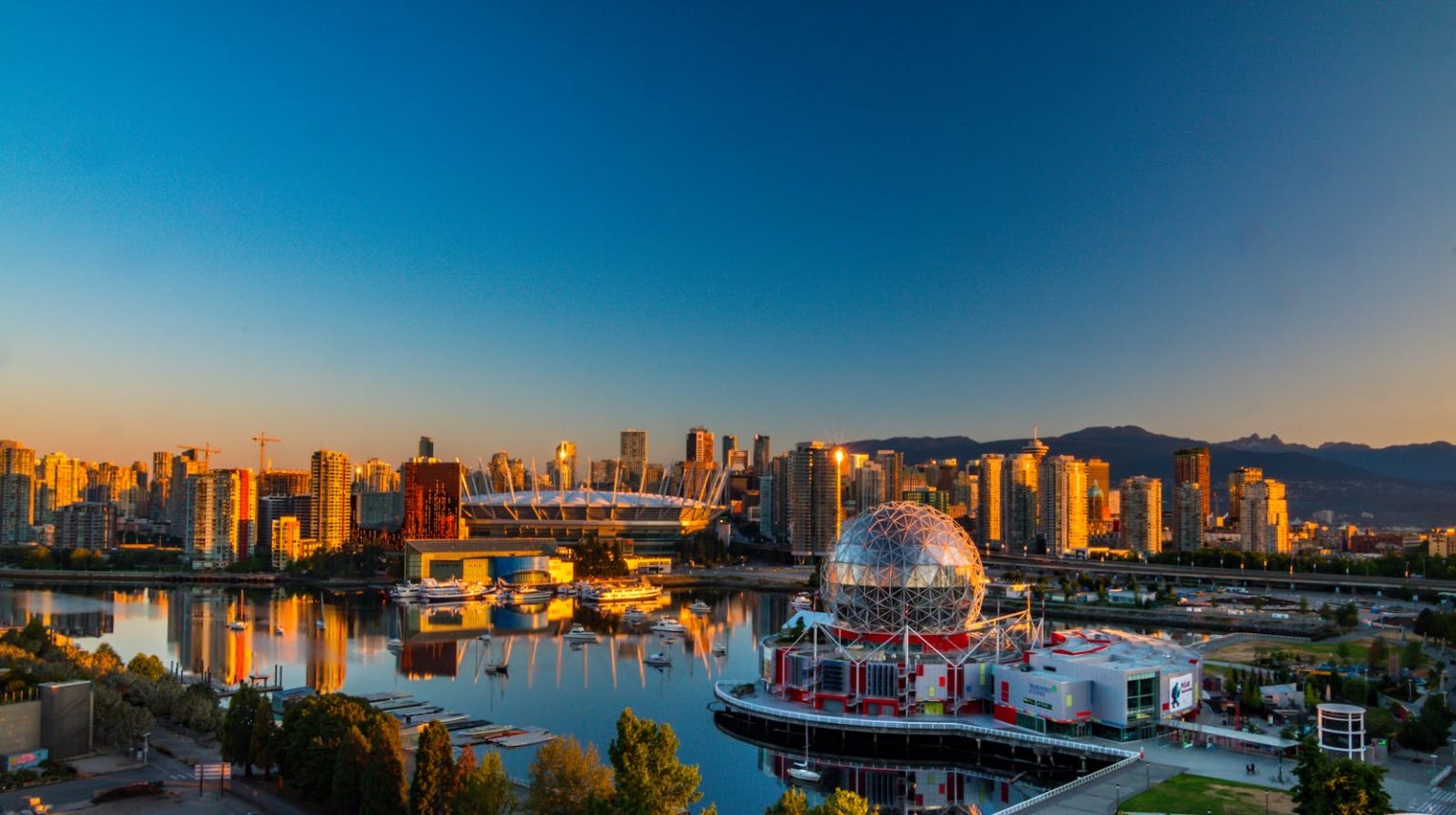 Vibrant sunset view of Vancouver's skyline, featuring Science World and cityscape reflections.