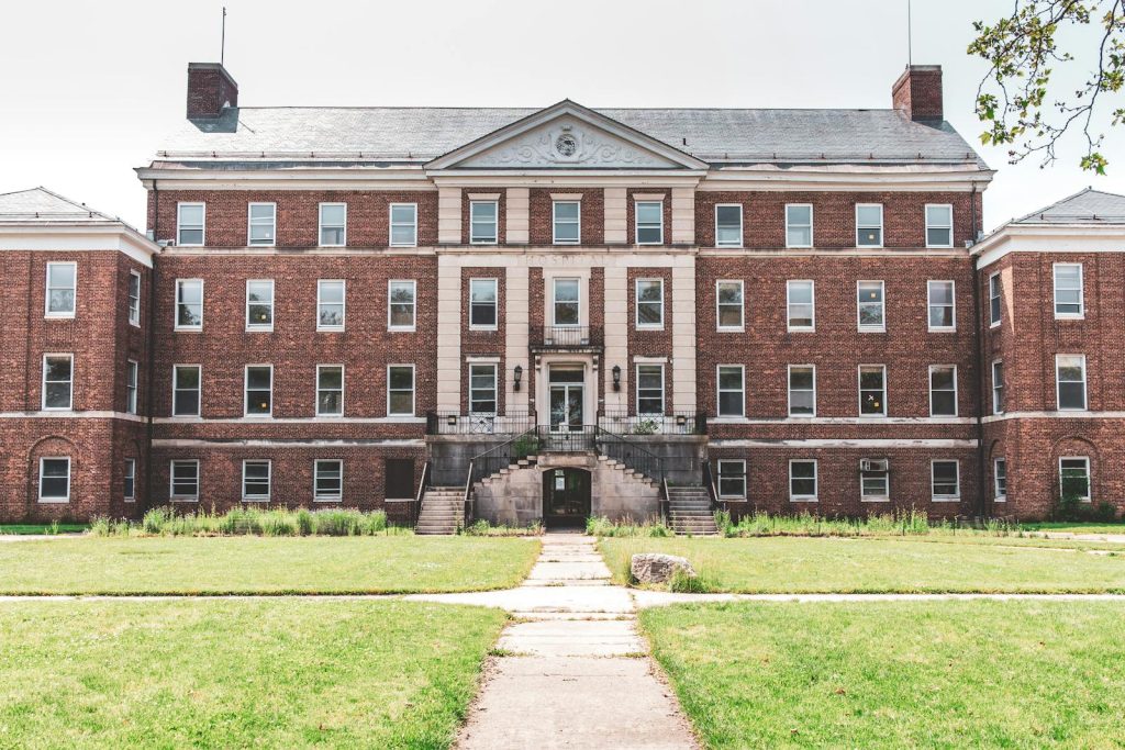 A historic brick building with classical elements, featuring a symmetrical facade and expansive lawn.