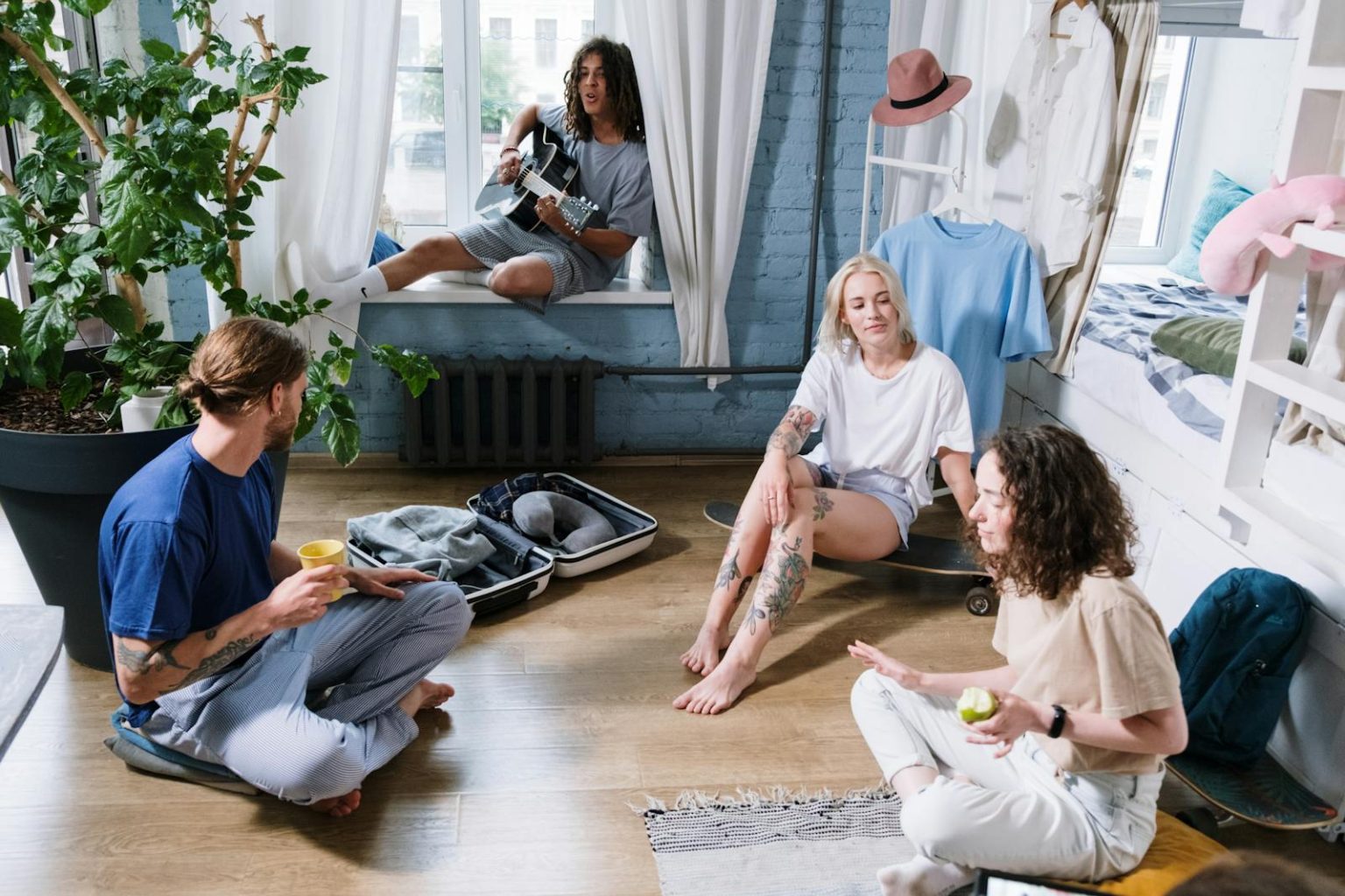 Group of friends enjoying a cozy indoor gathering with music and relaxation in a stylish bedroom.