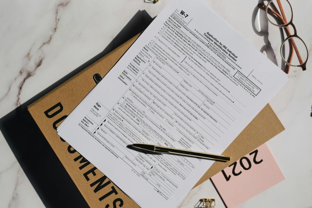 Top view of a tax form with a pen and eyeglasses on a marble surface, perfect for finance themes.