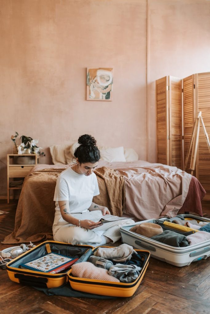 Woman organizing clothes in suitcase on bedroom floor, creating a relaxed travel vibe.