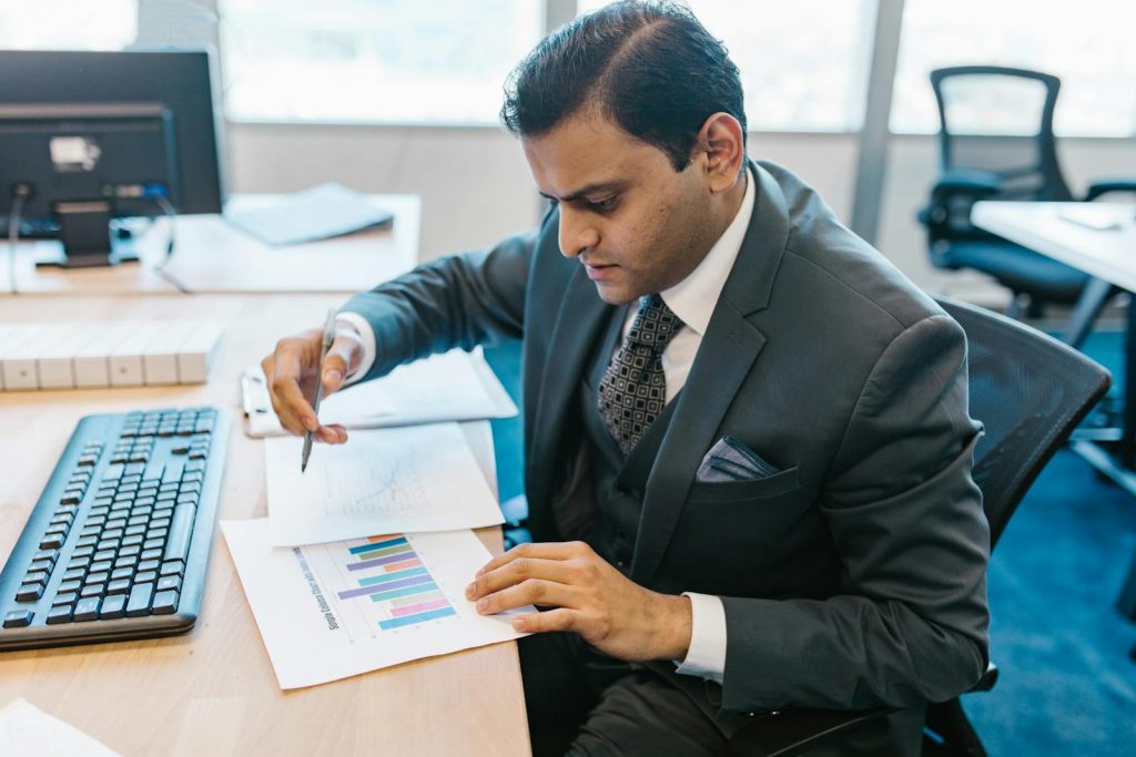 Business professional reviewing graphs and charts on a desk in a modern office setting.