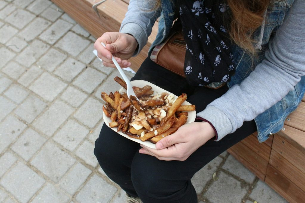 person holding burger with fries